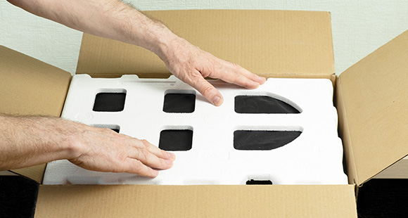 hands placing packaging foam in an open cardboard box showcasing protective interior material for delicate items related to 5 star delivery service