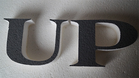 letters forming the word UP on a white textured background featuring two distinct colors of black and white