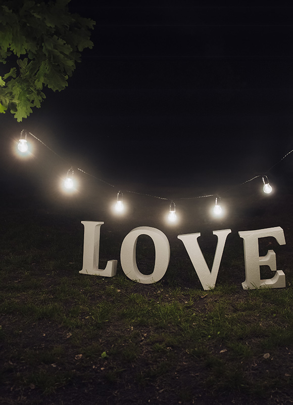 decorative lights illuminating the word love in a dark setting with green grass and a tree nearby perfect for romantic evenings or celebrations connected to the number 7